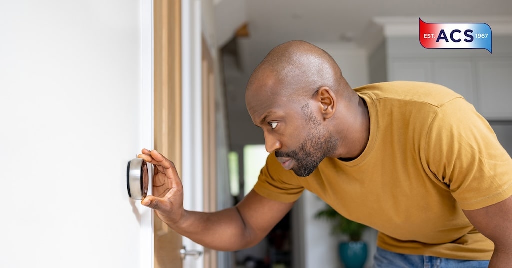 Why Choose a Smart Thermostat for Your HVAC System Man adjusting the smart thermostat in the home